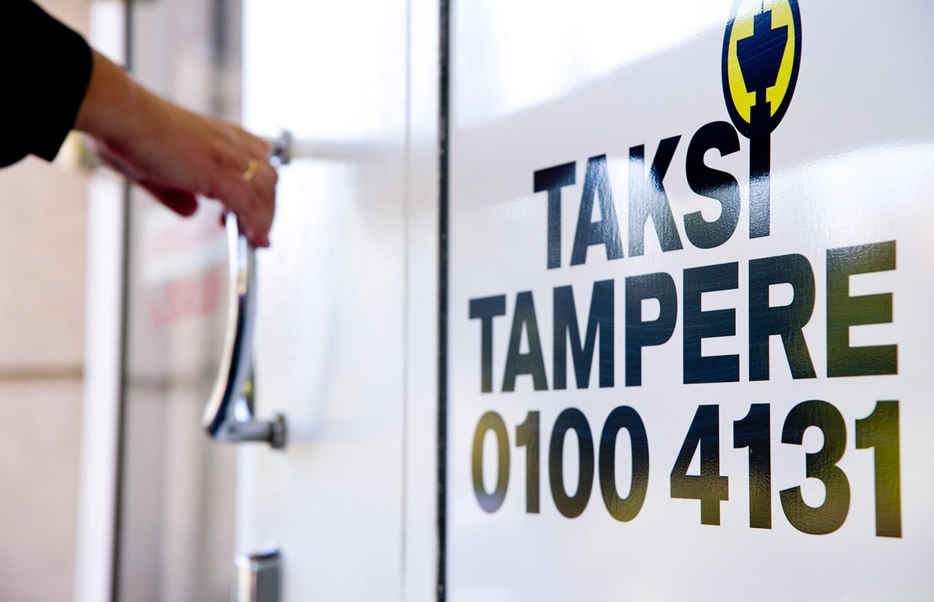 Kuvassa naisen käsi oven kahvassa ja valkoisella seinällä on Taksi Tampere -logo.