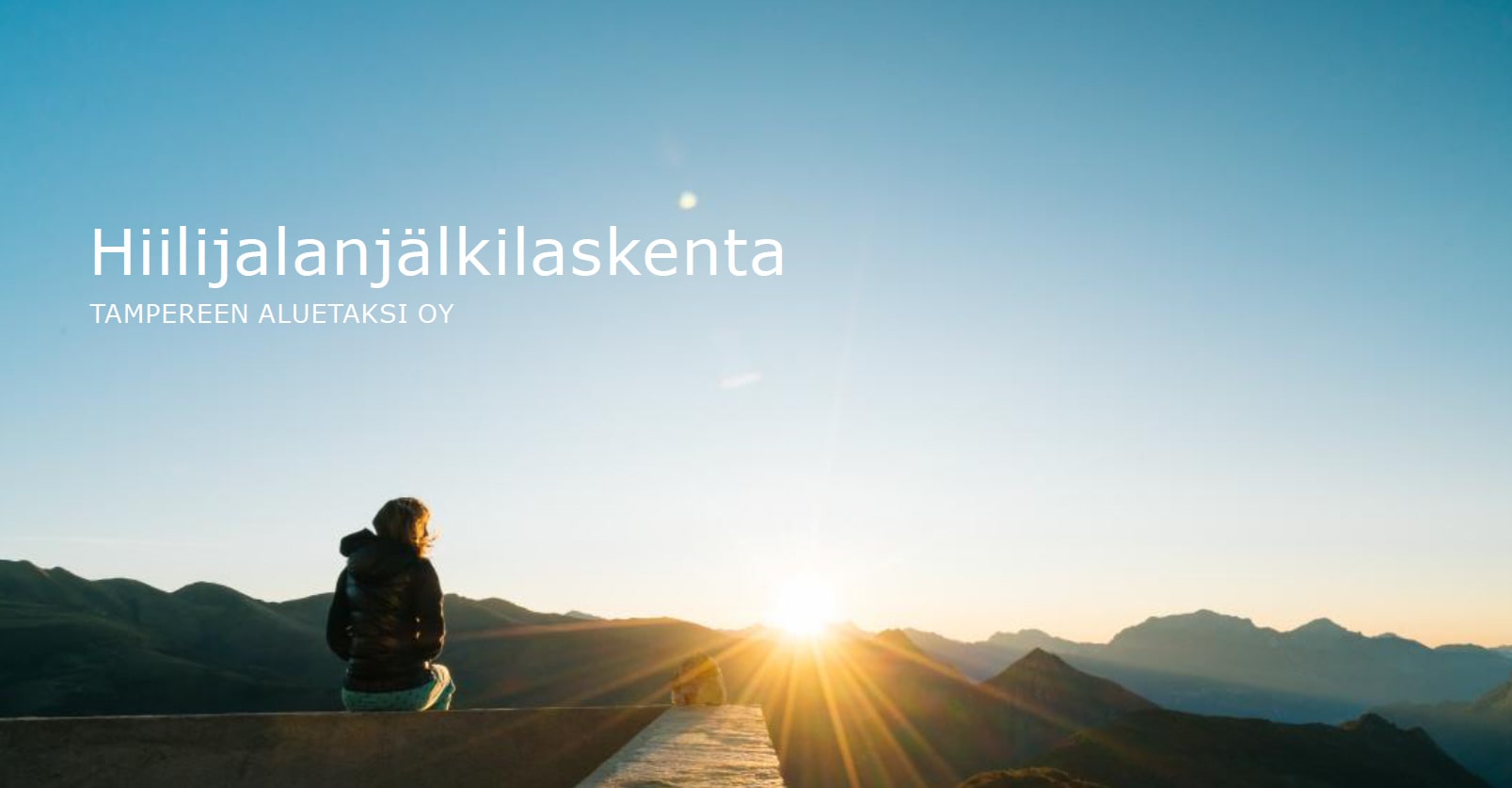 Maisemakuva, jossa ihminen katsoo auringonlaskua. Kuvassa teksti: "Hiilijalanjälkilaskenta, Tampereen Aluetaksi Oy".