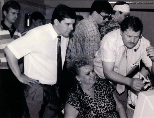 Kuva vuodelta 1991. Kuvassa seitsemän miestä ja nainen. Kuvassa yhdellä miehellä on kuulokkeet, joista hän välittää ensimmäistä tietokonepohjaista kyytiä Tampereella.