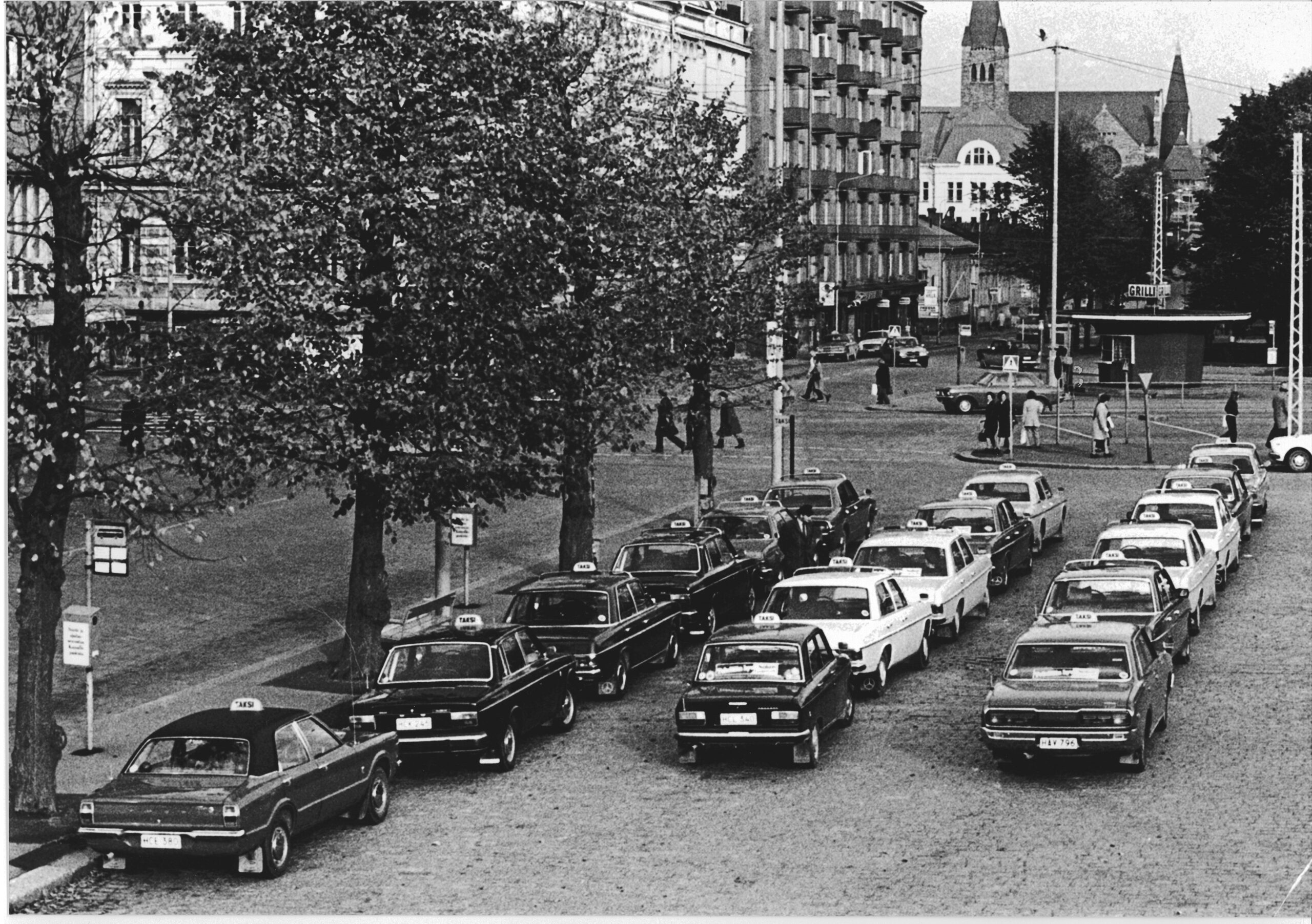 Kuvassa paljon taksiautoja Rautatieaseman taksiasemalla. Kuva on 1970-luvulta.